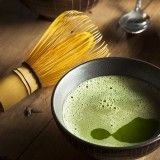 bamboe klopper voor traditionele bereiding van matcha thee met groen schuim in keramische kom