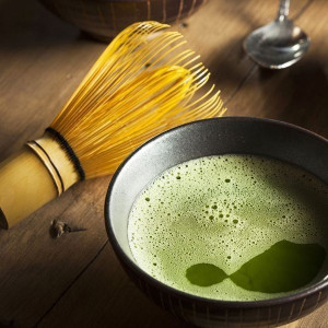 Bambusbesen für die traditionelle Zubereitung von Matcha – cremig-grüner Schaum in einer Keramikschale