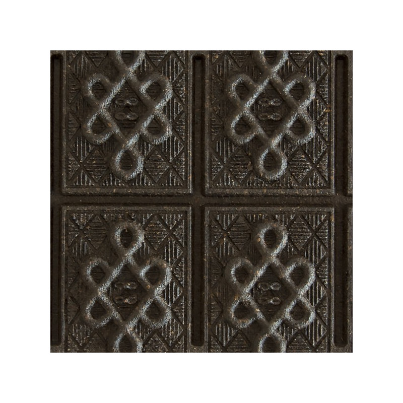 gecomprimeerde Pu Erh thee steen met geometrische reliëfpatronen op donker oppervlak