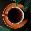 kopje zwarte Pu Erh thee in een oranje kop op een houten tafel