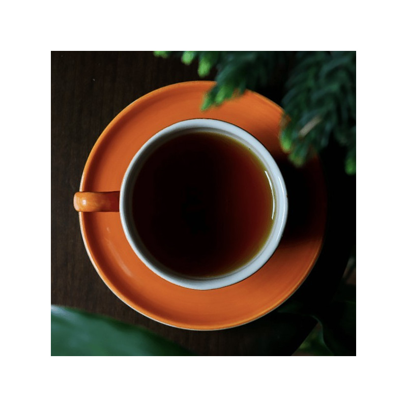 tasse de thé Pu Erh noir dans une tasse orange sur une table en bois