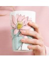 Thee-infuser Padma met roze lotusbloem motief vastgehouden in een hand op roze achtergrond