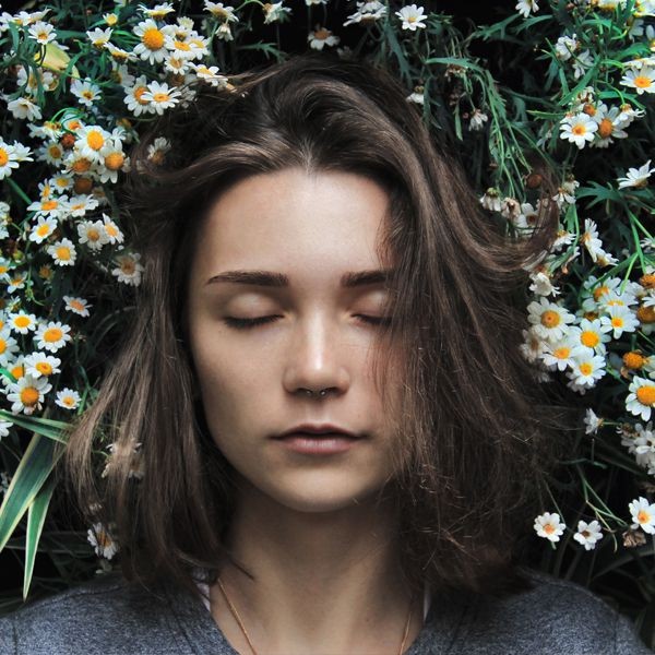 donna con occhi chiusi circondata da fiori bianchi e gialli per tisana CBD sonno Thés & Traditions