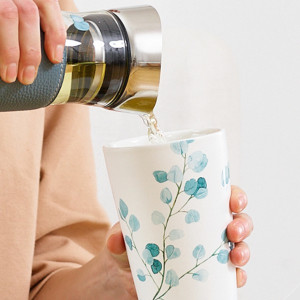 Tisanière Tree Eukalyptus gießt Aufguss in weiße Tasse mit blauem Blattdekor
