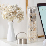 Glazen theepot Tropic Summer met gouden bladmotieven en roestvrijstalen filter op een witte tafel