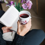 Porseleinen theemok met kersenbloesemmotief met een roodachtige infusie