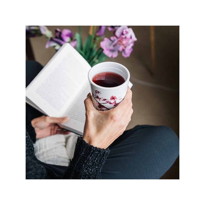 Tazza infusore in porcellana motivo fiori di ciliegio contenente un'infusione rossastra