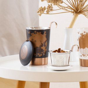 Komorebi Zwarte theekan met stalen infuser en Japanse motieven op witte tafel met vaas en droogbloem