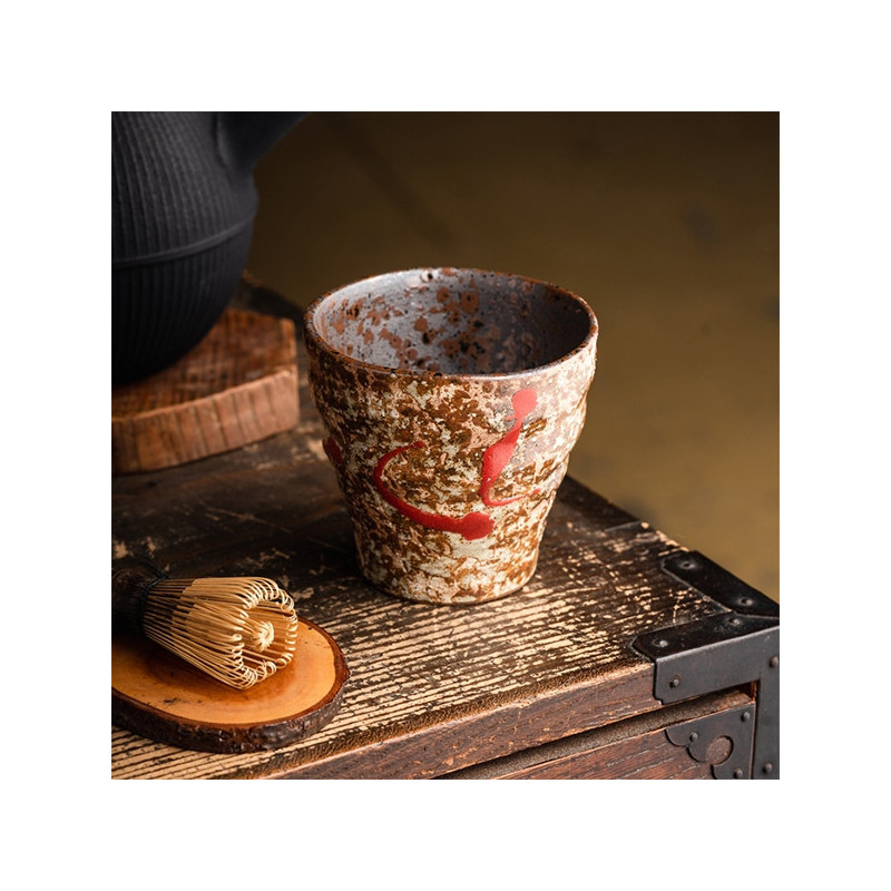 Akai Shibori ceramic cup with red patterns and rustic texture on wooden table