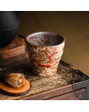 Akai Shibori ceramic cup with red patterns and rustic texture on wooden table