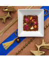 Mischung aus Rooibos mit Rosenblütenblättern und Zitrusfruchtstücken auf festlichem Hintergrund mit goldenen Dekoelementen