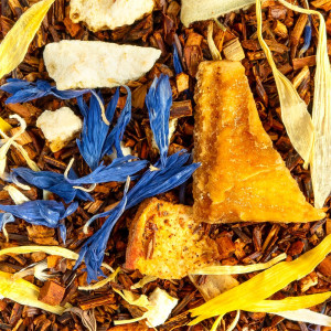Mischung aus rotem Rooibos, blauen Blütenblättern, getrockneten Fruchtstücken und gelben Schalen