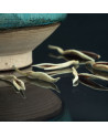 Yin Zhen Silverneedle white tea buds on black surface with turquoise ceramic bowl