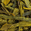 Gedroogde bladeren van groene thee Earl Grey Sencha in groene en bruine tinten