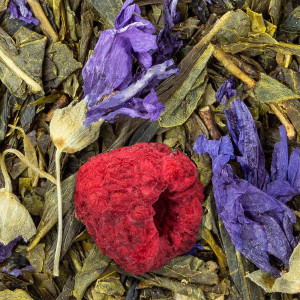 Grüntee Jardin de Paris mit grünen Blättern, violetten Blüten und getrockneter Himbeere