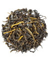 Dried yellow tea leaves with golden hues on a white background