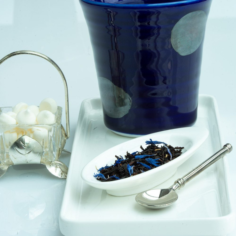 Blue Earl Grey black tea leaves with blue flowers on white spoon and blue cup