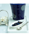 Blue Earl Grey black tea leaves with blue flowers on white spoon and blue cup