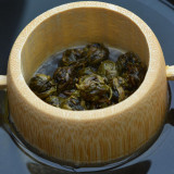 witte thee jasmijn parels Dragon Pearls in bamboe thee-ei op zwarte achtergrond