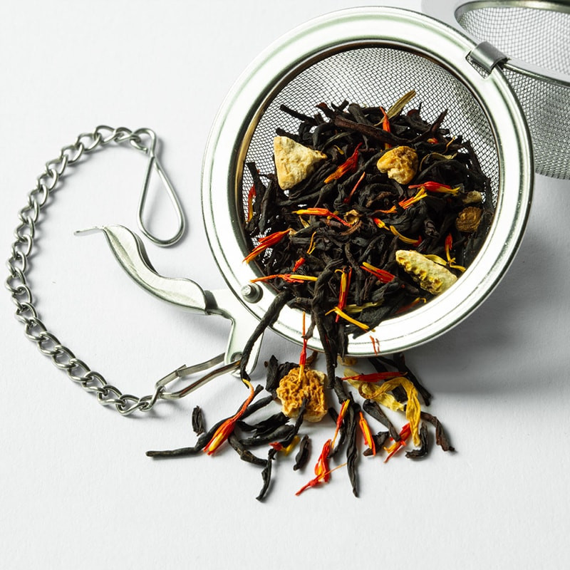 Stainless steel tea ball with black tea and dried flowers for infusion