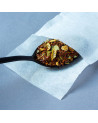 Empty white paper tea bag for infusion tea leaves and citrus pieces on black spoon