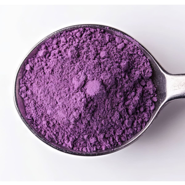 Fine purple ube powder in a metal spoon on white background