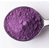 Fine purple ube powder in a metal spoon on white background