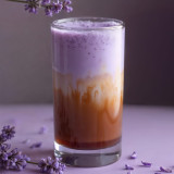 Paarse en bruine melkdrank met ube poeder en paarse bloemen eromheen