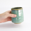 Tazza Kinyo in ceramica verde con bordo beige tenuta in una mano