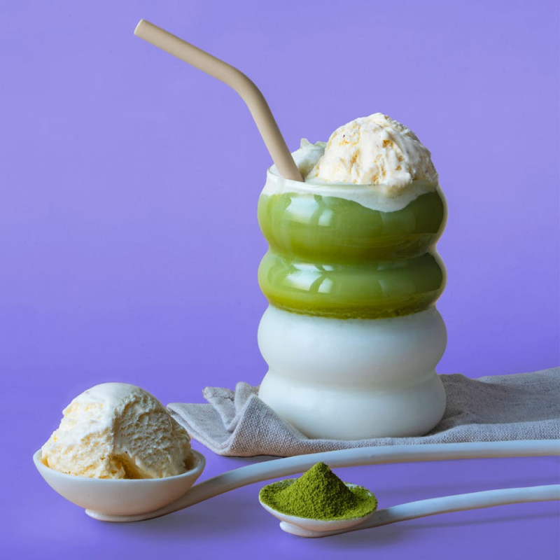 Bevanda matcha vaniglia con ghiaccio, polvere di matcha e gelato alla vaniglia su sfondo viola
