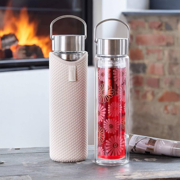 Glaskanne Flowtea Amami mit Blumenmuster-Sieb und beiger Schutzhülle auf Holztisch