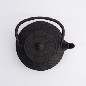 Black cast iron teapot with curved handle and arare style textured surface