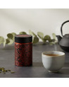 Schwarze Teedose Mandala Ebony mit roten Blütenmotiven auf schwarzem Grund neben einer dampfenden Teetasse