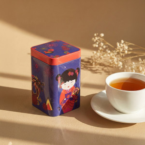 Teedose Sweet Little Geisha Fire mit Geisha- und Drachen-Illustration neben einer Tasse Weißtee