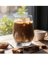 Glas mit Bio-Hojicha-Grüntee auf Eis mit Eiswürfeln auf hellem Holztisch