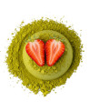 Poudre de matcha vert avec deux moitiés de fraise rouge posées dessus
