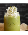Matcha-Latte mit Haselnussschokolade, Schlagsahne und grünem Teepulver in einem transparenten Glas