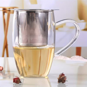 Infuseur à thé en inox posé sur tasse en verre avec infusion claire et poignée ergonomique