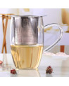 Stainless steel tea infuser resting on a glass cup with light infusion and ergonomic handle
