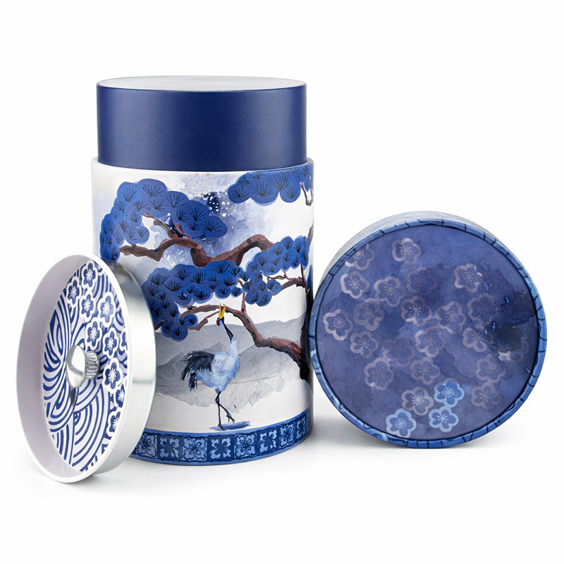 Round tea tin with blue crane and tree design, lid adorned with blue floral motifs