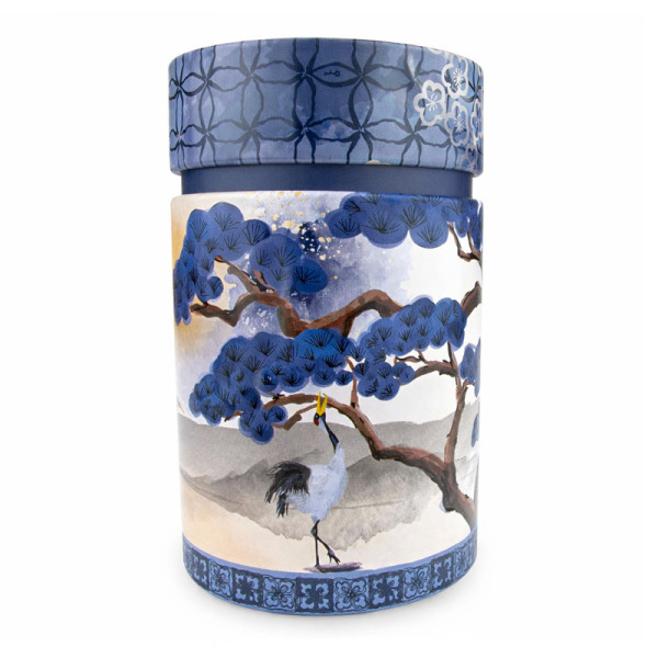 Round tea tin decorated with a blue pine tree and a white crane on a mountain background
