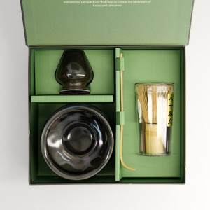 Top view of the open Kuro matcha gift set: black bowl, whisk holder and bamboo whisk in green case