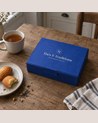 Thés & Traditions Gourmand Gift Set: blue box on a wooden table, with madeleines and a cup of tea