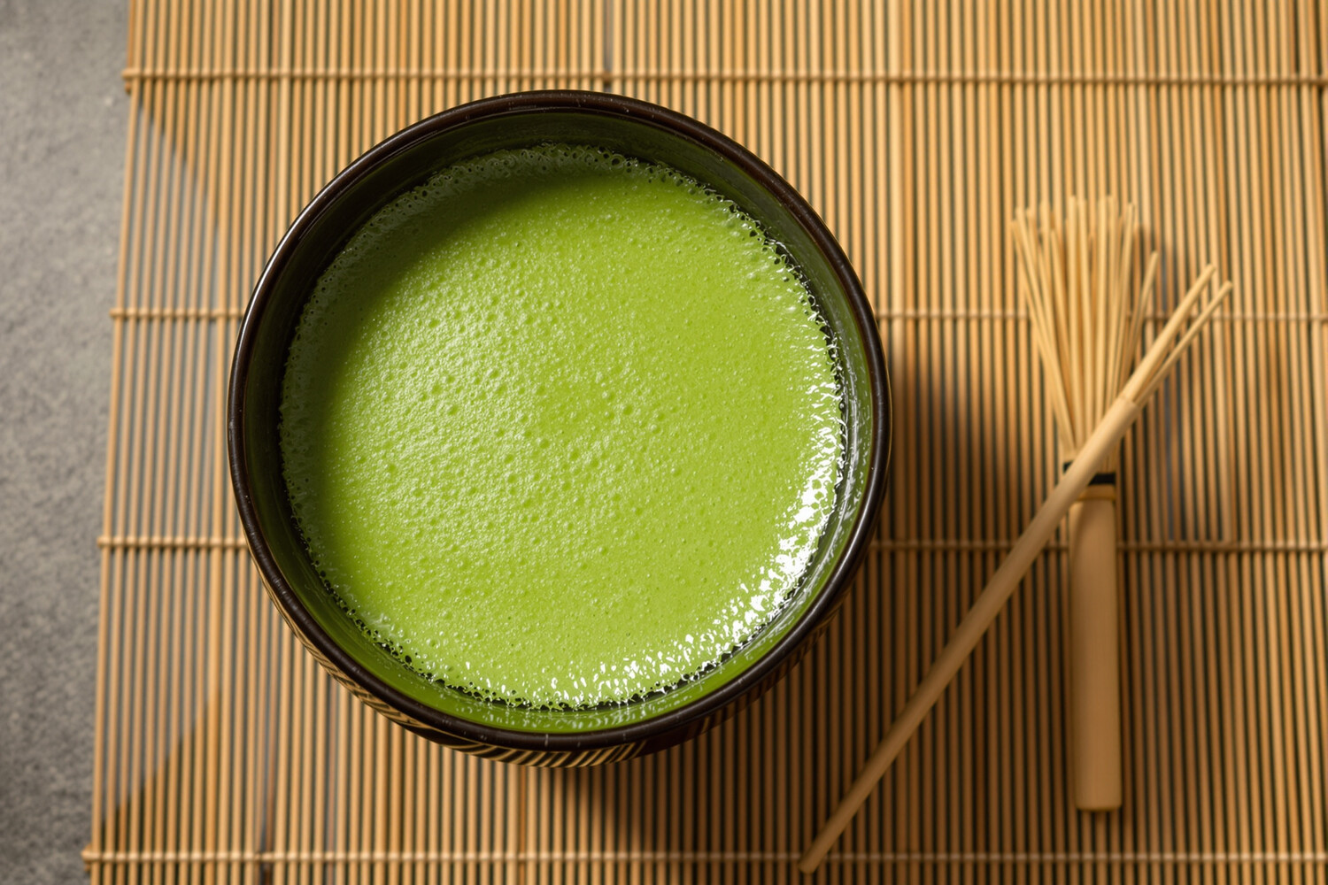 Bovenaanzicht van geklopte schuimende matcha in donkere keramische chawan-kom