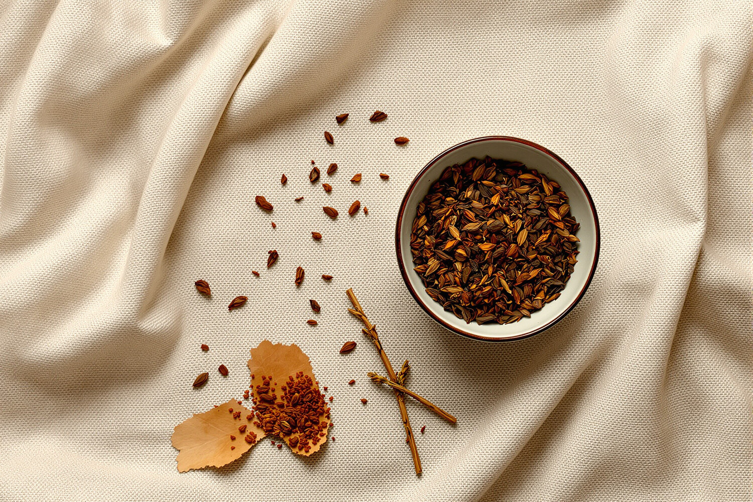 Stilleven van geroosterde hojicha-blaadjes in een keramieken kom op ecru linnen.